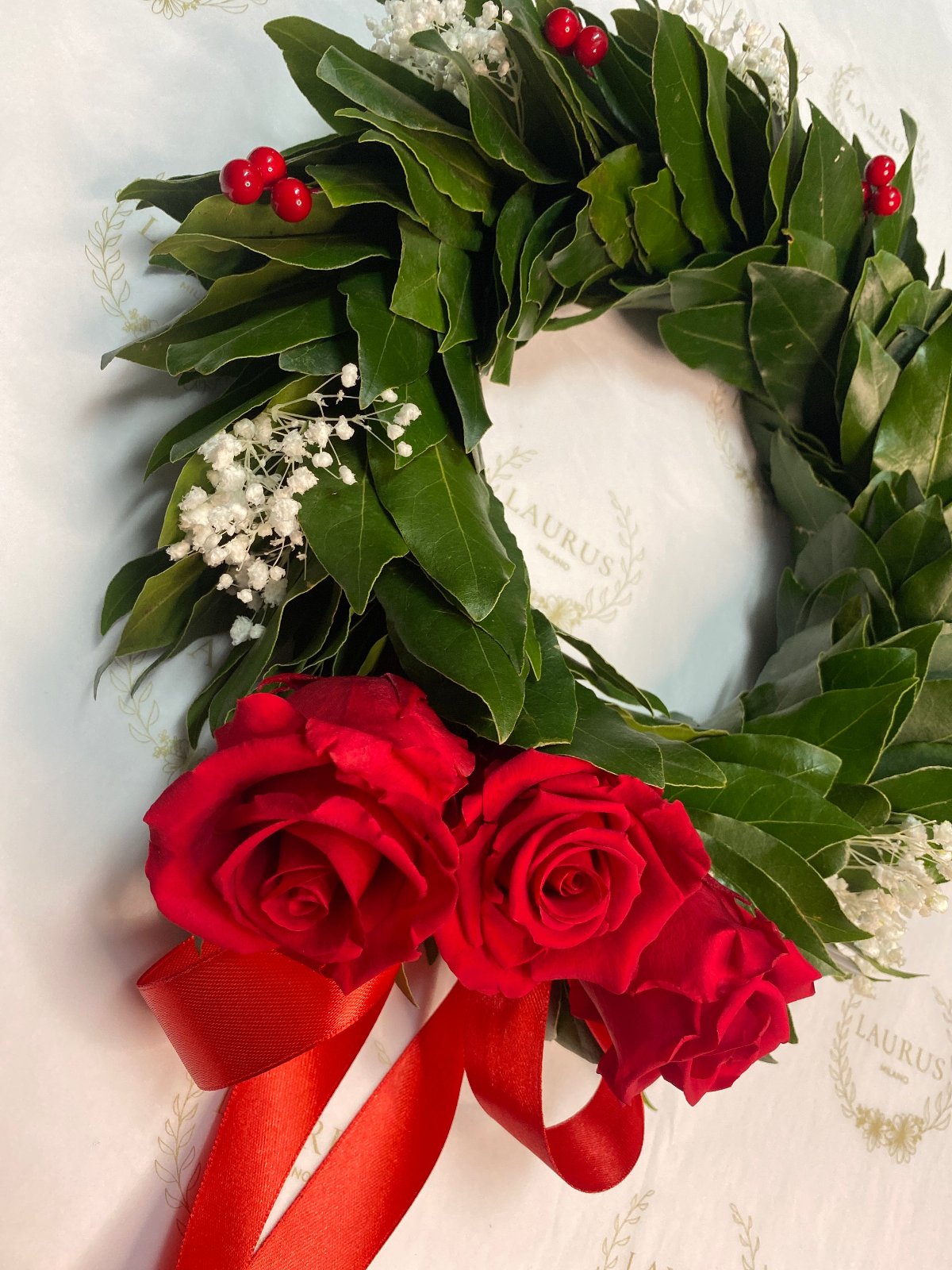 Corona d'Alloro - Bacche rosse, Gypsophila bianca e Rose rosse sul fiocco